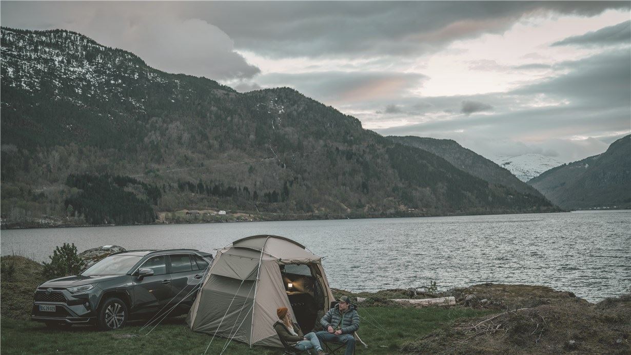 Tent pitched by the side of a lake with mountains
