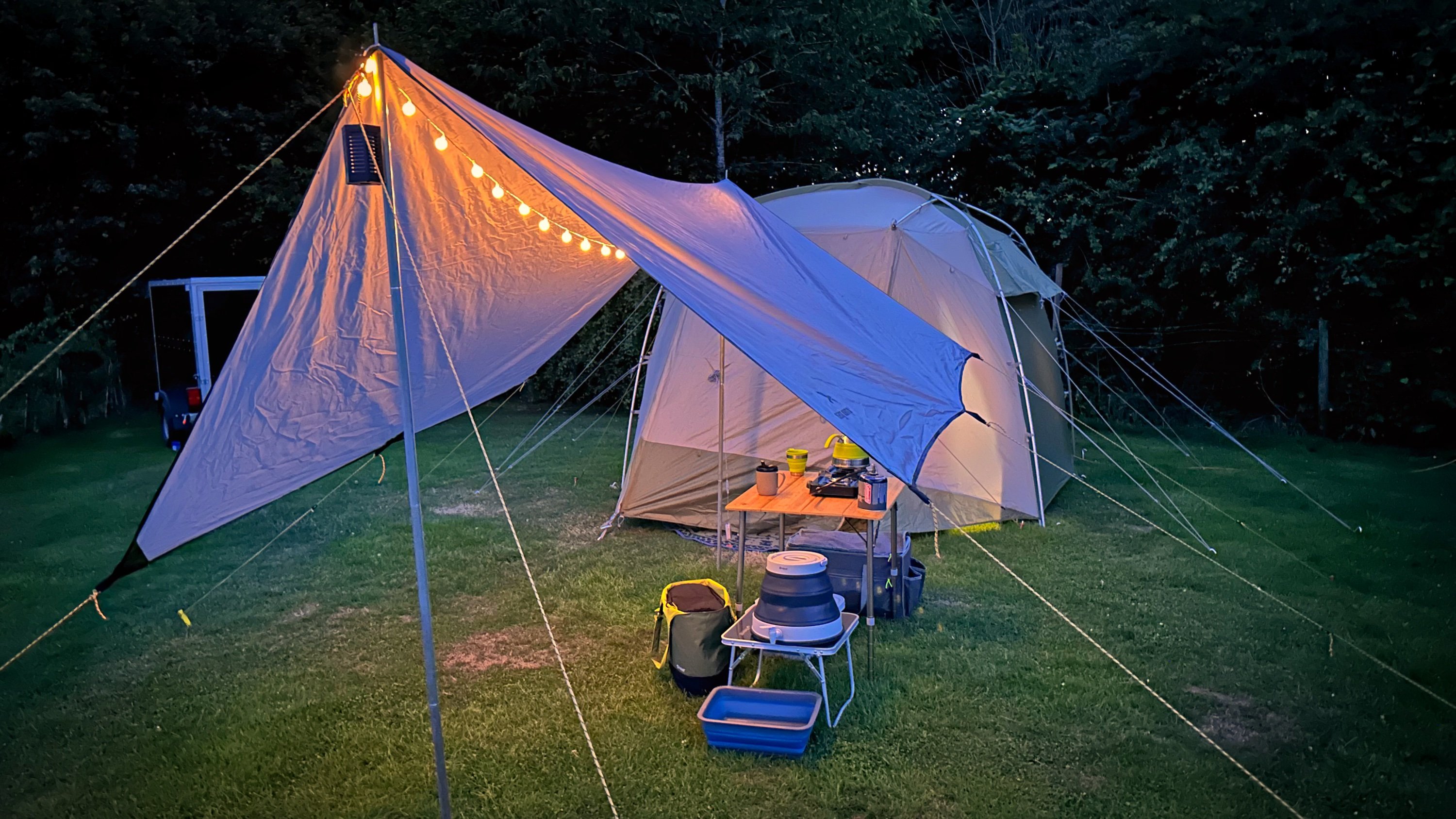 The tent pitched at night with a tarp and lights