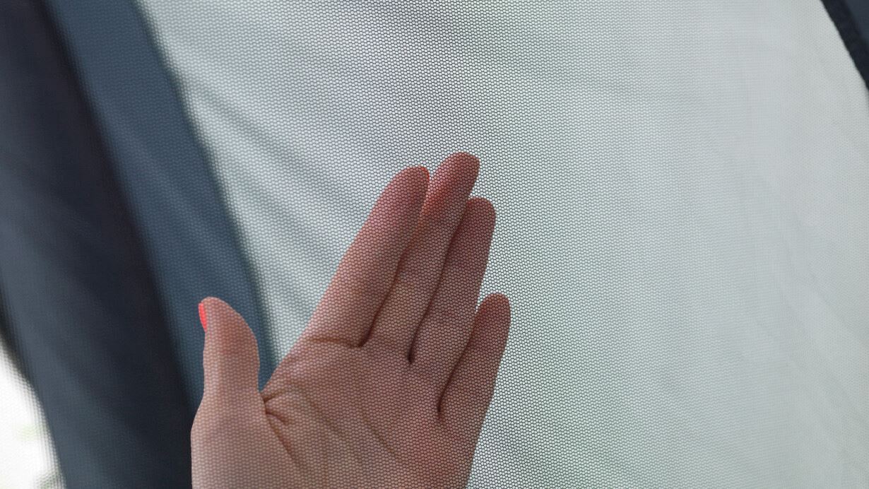 A hand over the tent's bug mesh