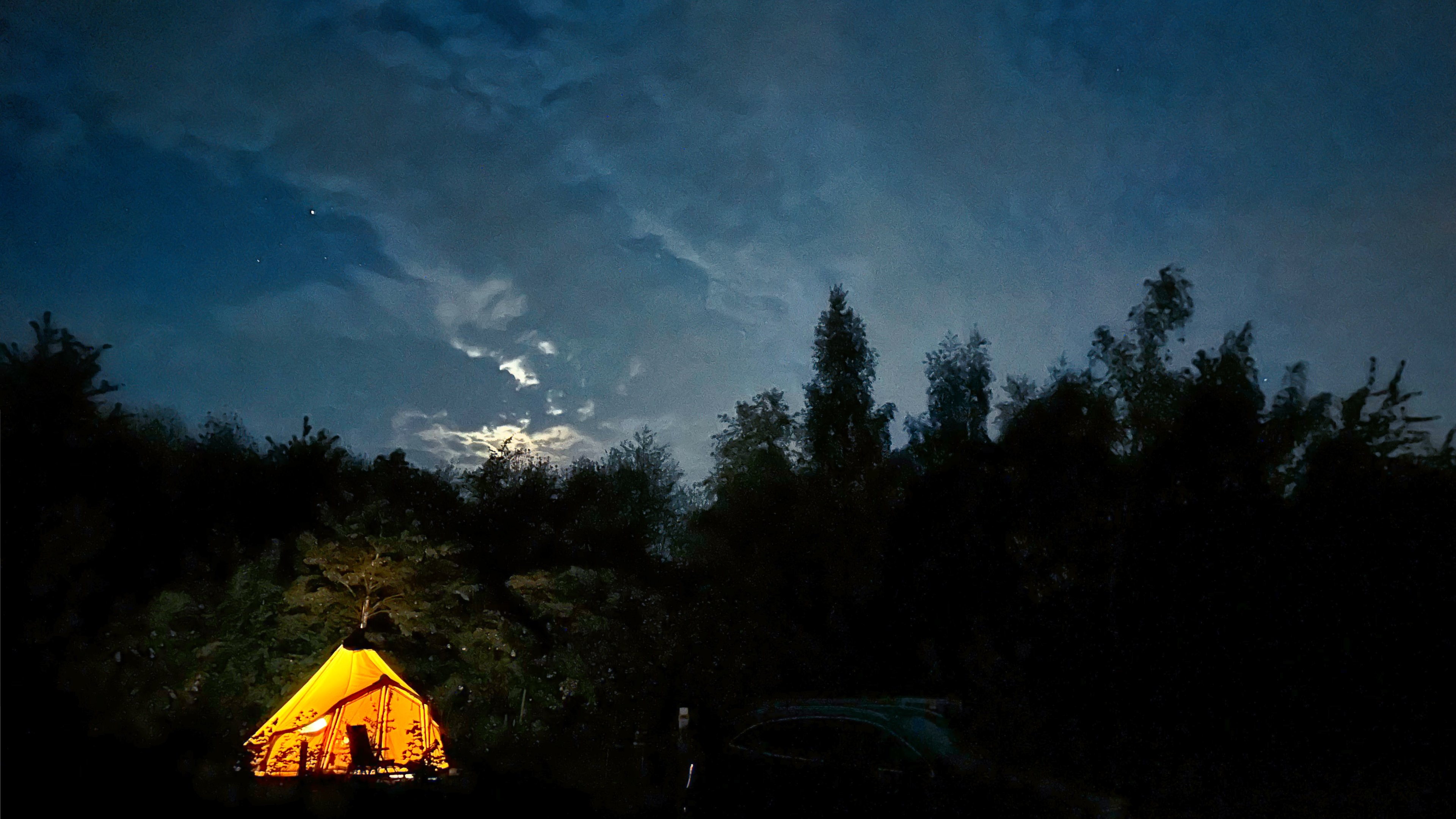 The tent lit up at night under the night's sky